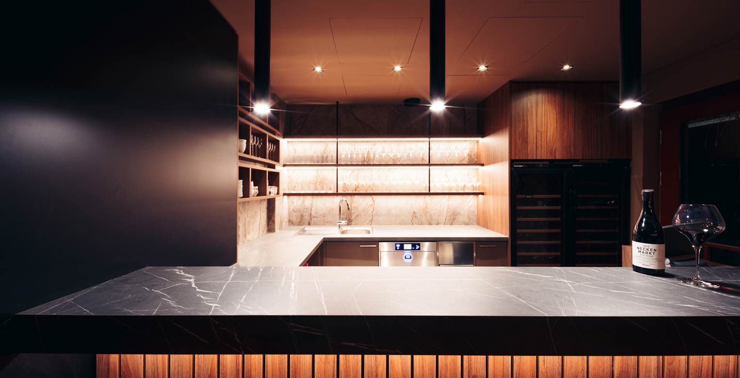 Moderne Bar mit Marmor-Theke, Glasregalen und einer Flasche Rotwein.