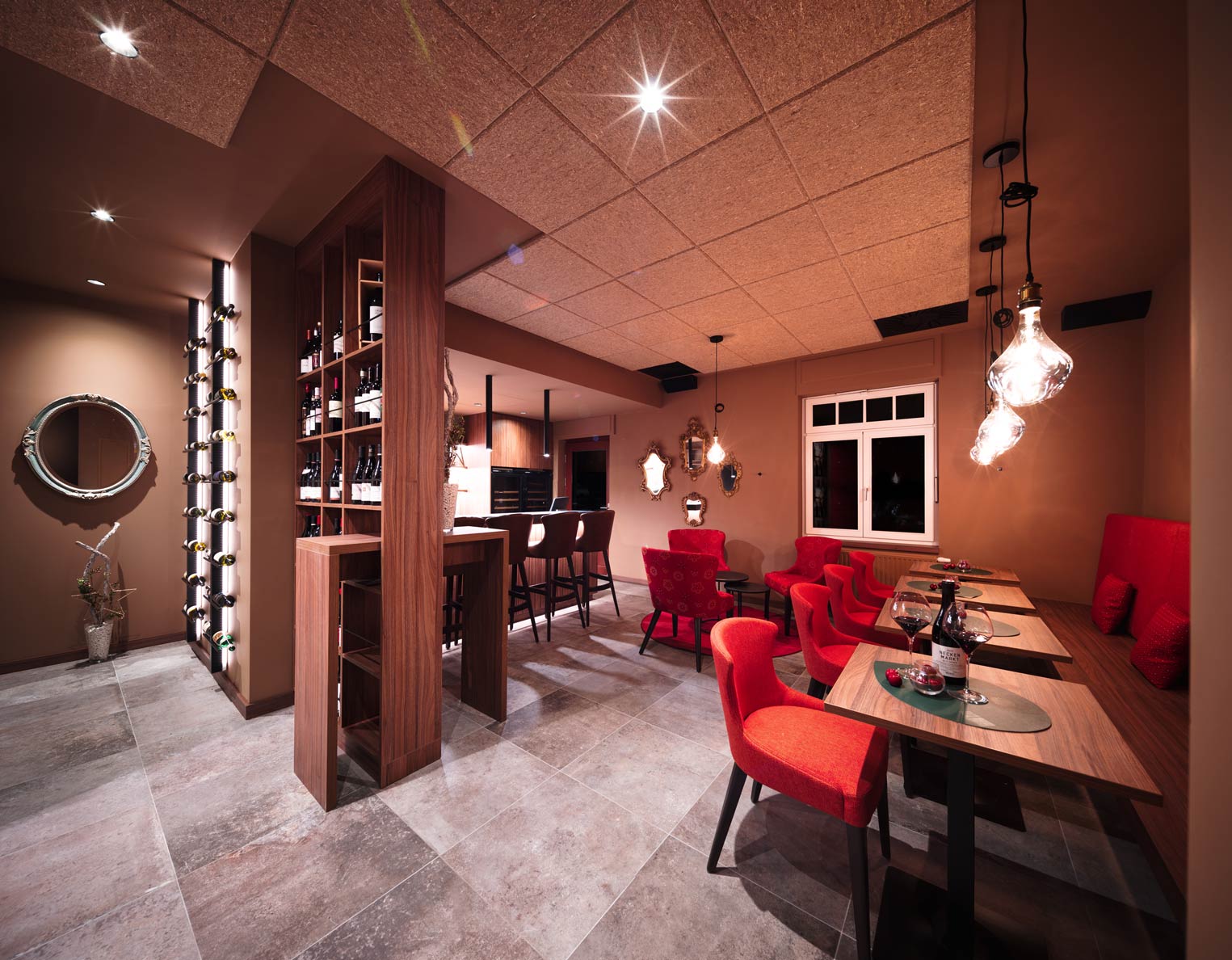 Elegante Weinbar mit roten Sitzmöbeln, Holzregalen und moderner Beleuchtung.